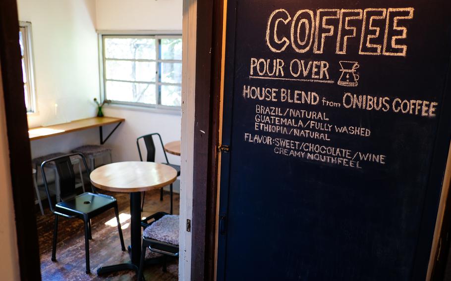 Cafe D-13's wood-finished interior, black pellet stove, reading nook, cozy rooms with seating, and displayed baked goods create a soothing atmosphere perfect for sipping coffee over a book or quietly chatting with a friend.