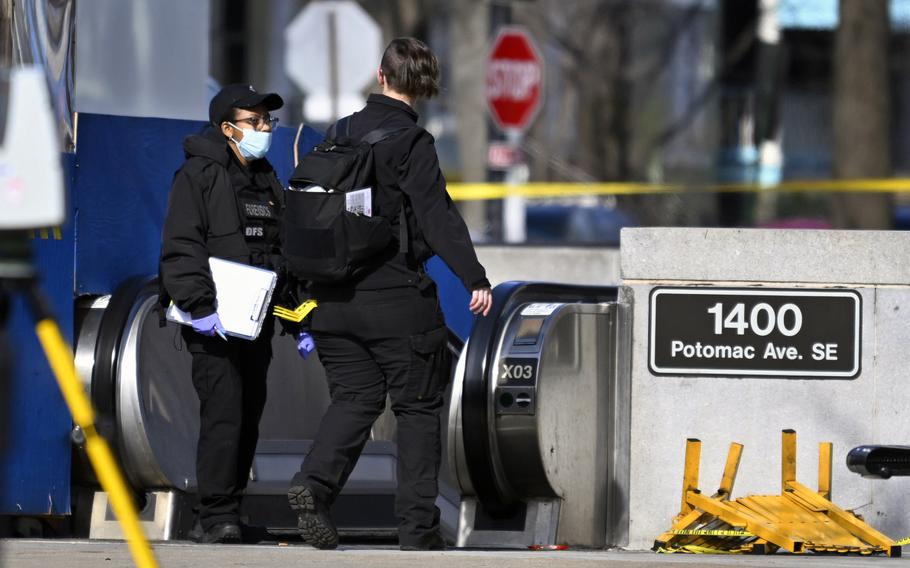 Members of the D.C. Department of Forensic Sciences stand Wednesday at the entrance of the Potomac Avenue Metro station in Southeast Washington, where a shooter killed a Metro mechanic and injured three others.
