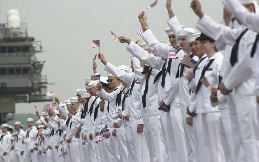 Kitty Hawk sailors wave American flags as the ship pulls into port Tuesday morning, May 6, 2003, after a four-month deployment to the Persian Gulf.