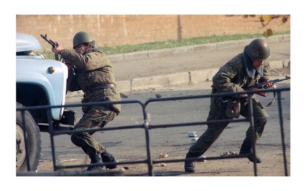 A Russian soldier fires his machine gun while another runs to take shelter during the assault aimed to flush out hard-line lawmakers and their supporters inside the parliament building in Moscow on Oct. 4, 1993. 