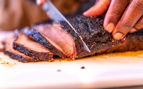 Barbequed meat is sliced to be served.