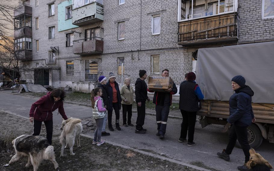 Residents wait as a delivery of food aid is unloaded at the Triangle.