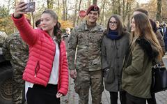 A Polish high school student takes a selfie with her friends and U.S. Army 1st Lt. Logan Gearhart of the 173rd Airborne Brigade, during static display in Lobez, Poland in 2016. International attitudes to the U.S. and NATO have improved since the beginning of the war in Ukraine, according to a new Pew Research Center global opinion survey. 