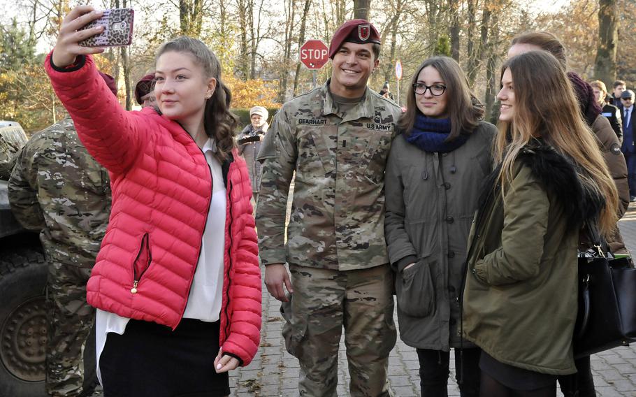 A Polish high school student takes a selfie with her friends and U.S. Army 1st Lt. Logan Gearhart of the 173rd Airborne Brigade, during static display in Lobez, Poland in 2016. International attitudes toward the U.S. and NATO have improved since the beginning of the war in Ukraine, according to a survey. 