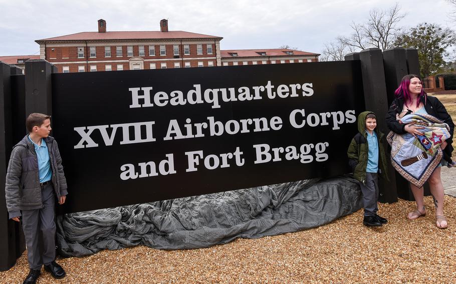 Three people stand on either side of a sign. 