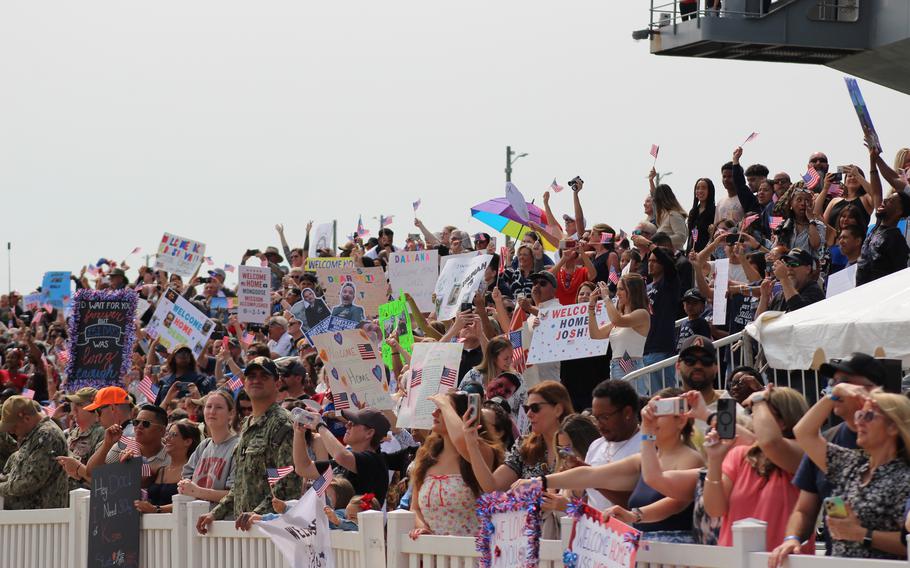 A crowd of people hold banners behind a gate