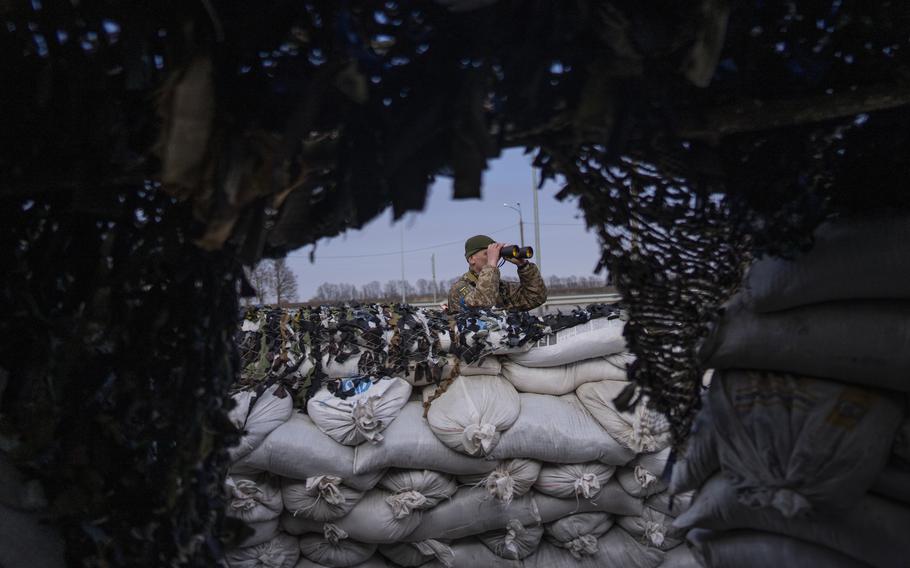 A Ukrainian soldier looks through binoculars at a military check point, in Lityn, Ukraine, Wednesday, March 16, 2022. 