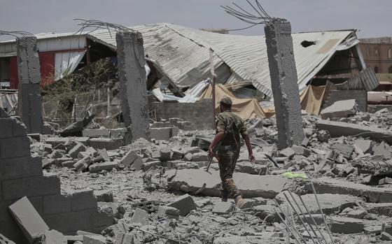 A soldier walking through rubble.