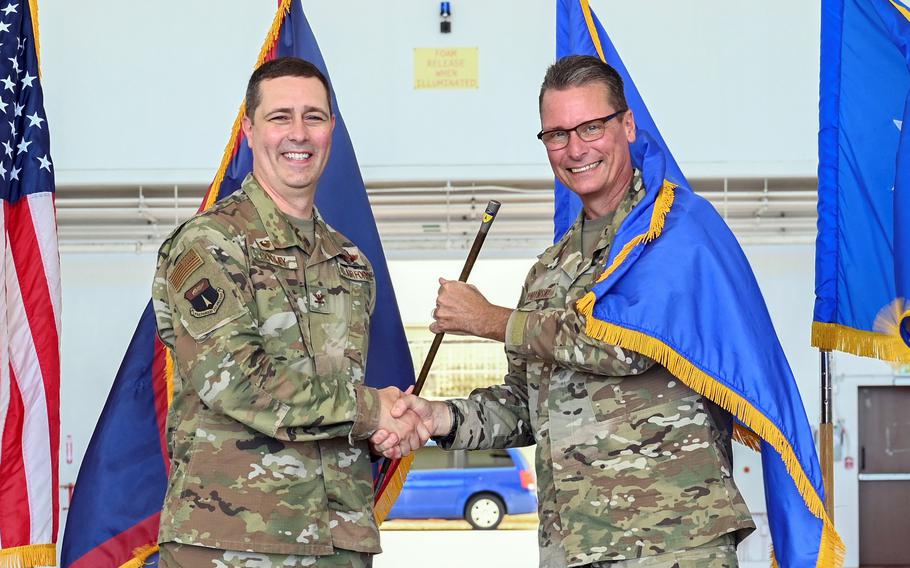 Two uniformed officers pose for a picture in front of four flags, including the U.S. flag and the Guam territorial flag.