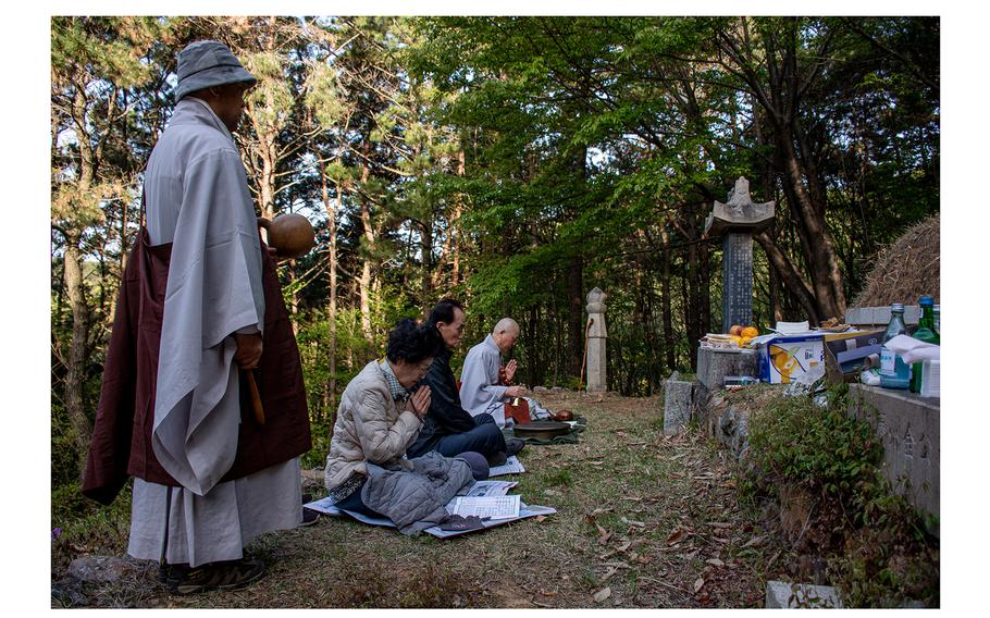 Buddhist monks perform blessing prayers in honor of Lee Jong-wook as the Lee family gathers at his original burial plot, in Busan. 