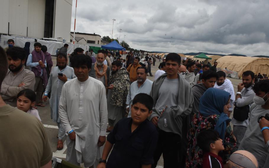 Evacuees from Afghanistan congregate inside a temporary living facility on the flight line at Ramstein Air Base, Germany. About 7,000 evacuees had arrived by Monday, while some U.S. citizens and families left on flights to the United States.