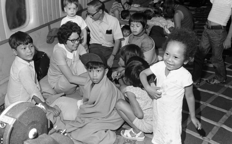 Children, some wrapped in blankets, seen on the floor of a plane while a couple of adults attend to them.