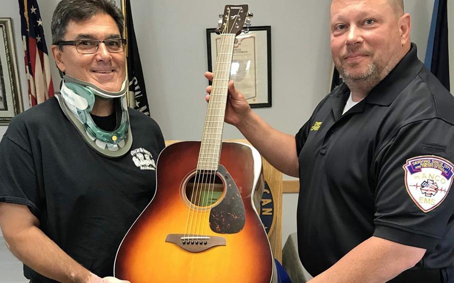 An Air Force veteran identified as Gordon M., left, receives a free guitar after completing 10 free lessons from Guitars4Vets, a Wisconsin-based charity that helps veterans overcome post-traumatic stress disorder through music.