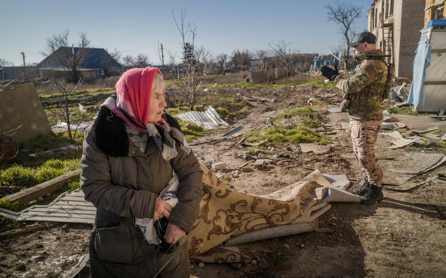 Yaroslava Kusherenko, 81, carries a carpet from a kindergarten in Oleksandrivka to use in her home, which has no heat.