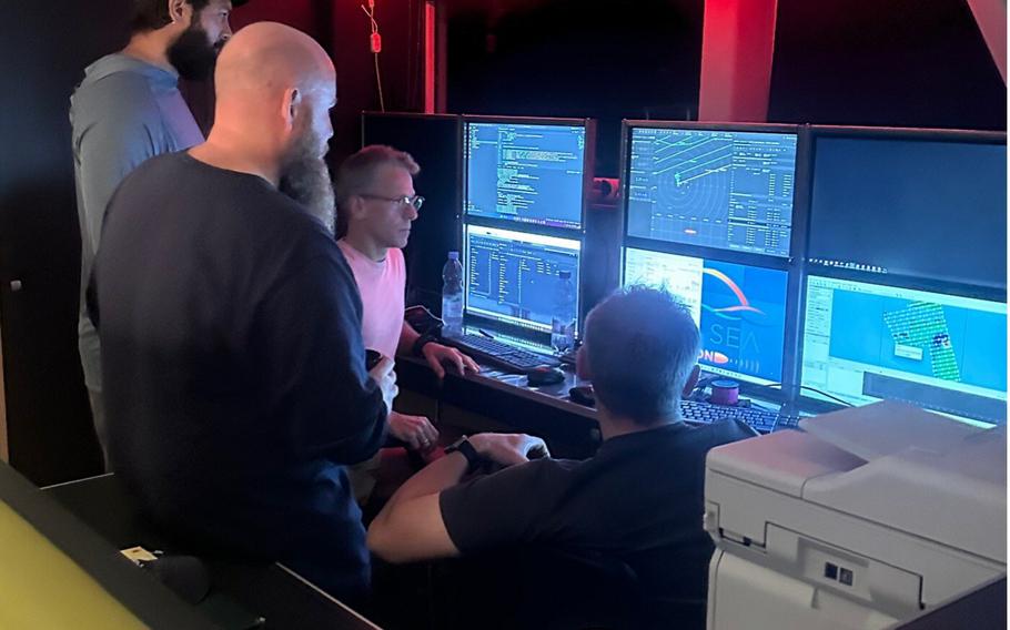 The Deep Sea Vision team gathers around for review of data returning from sonar system when the system returns to the surface. Due to the amount of data collected a thorough review of all the sea floor imagery can take days to complete.