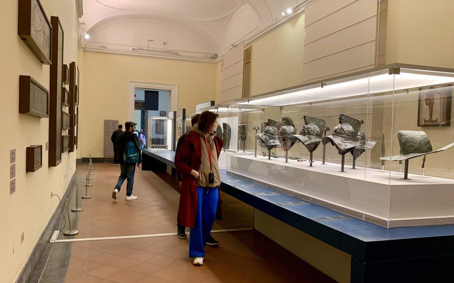 People look at a display of artifacts in an encasing.