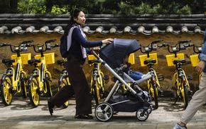A woman pushes her child in a stroller past rental bicycles in Seoul on April 26, 2024. (Anthony Wallace/AFP/Getty Images/TNS)