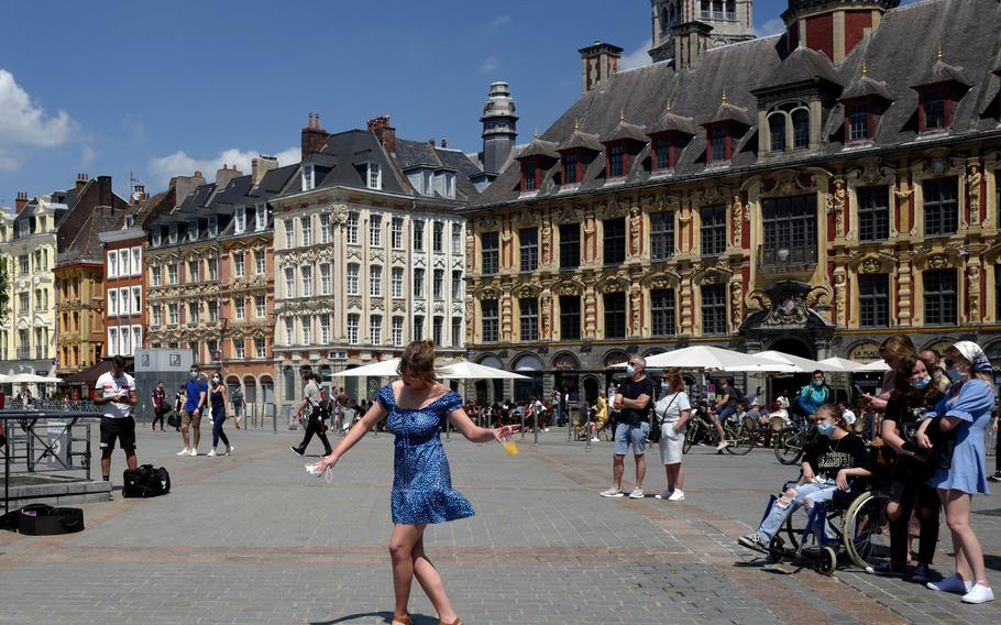 A woman dances by a cafe terrace in Lille, northern France, French tourism seeks new boost with Disneyland reopening. In France, authorities said it’s no longer always mandatory to wear masks outdoors.