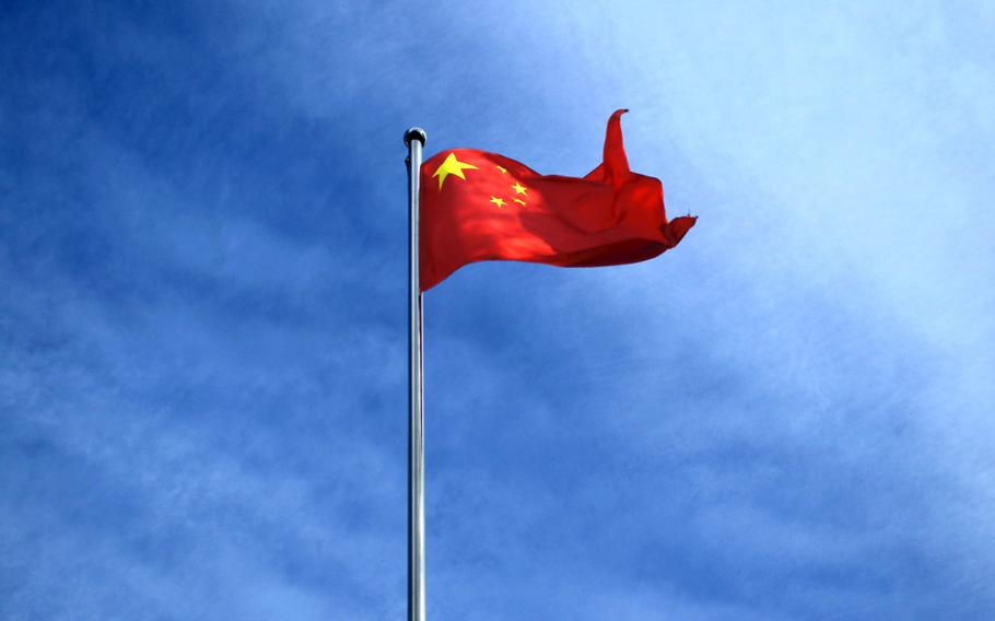 A Chinese flag flies in front of a blue sky.