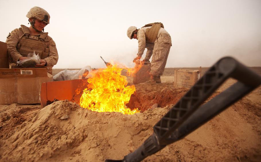 Marine Lance Cpl. Nathanial Fink (left) and Lance Cpl. Garrett Camacho dispose of trash in a burn pit in 2012 in Afghanistan.
