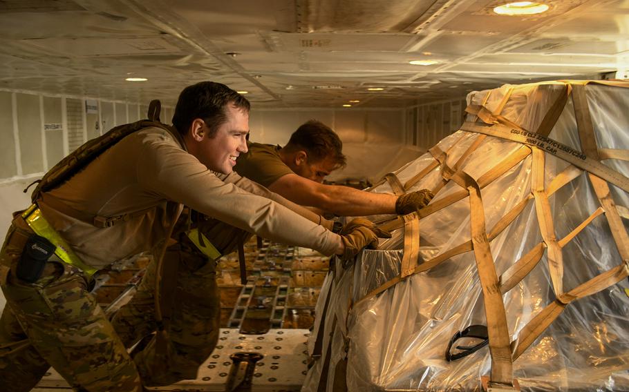 Senior Airman Robin Mercer and Staff Sgt. Colton Panizo push a pallet of humanitarian aid off a cargo plane while deployed to Incirlik Air Base, Turkey, Feb. 22, 2023. Mercer, normally assigned to the 721st Aerial Port Squadron in Ramstein Air Base, Germany, deployed to Turkey on short notice in the aftermath of the Feb. 6 earthquakes.