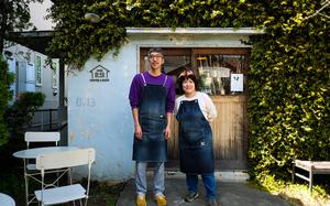 Megumu Gomi, left, and his wife, Megumi, pose outside D-13, a cafe they founded in an old flat house used as service member housing near Yokota Air Base, Japan.