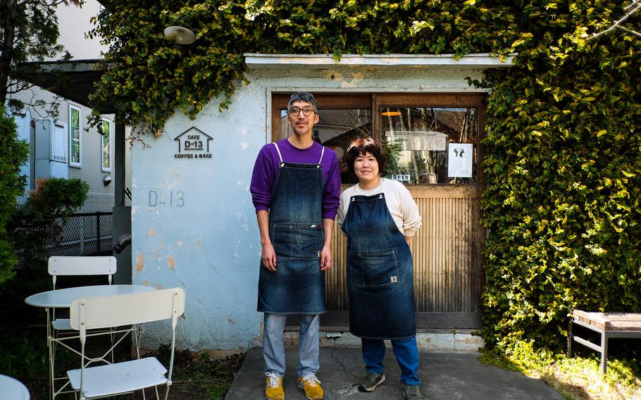 Megumu Gomi, left, and his wife, Megumi, pose outside D-13, a cafe they founded in an old flat house used as service member housing near Yokota Air Base, Japan.