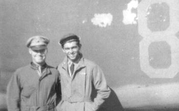 Two airmen post in front of a bomber in a black and white photo.