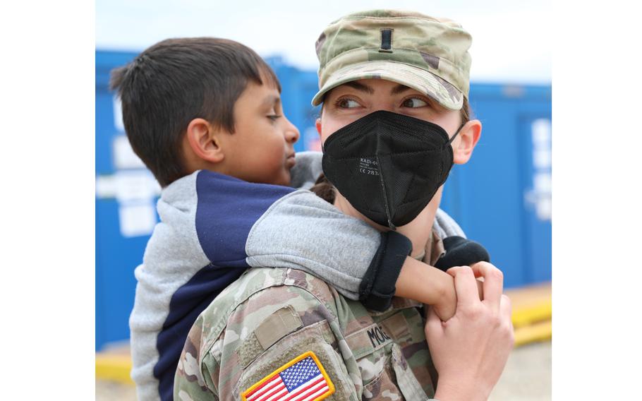 U.S. Army 1st Lt. Alexandria Moore, Task Force Ever Vigilant, carries a young Afghan evacuee on her back while providing a tour of Camp Liya, Kosovo, Oct. 1, 2021.