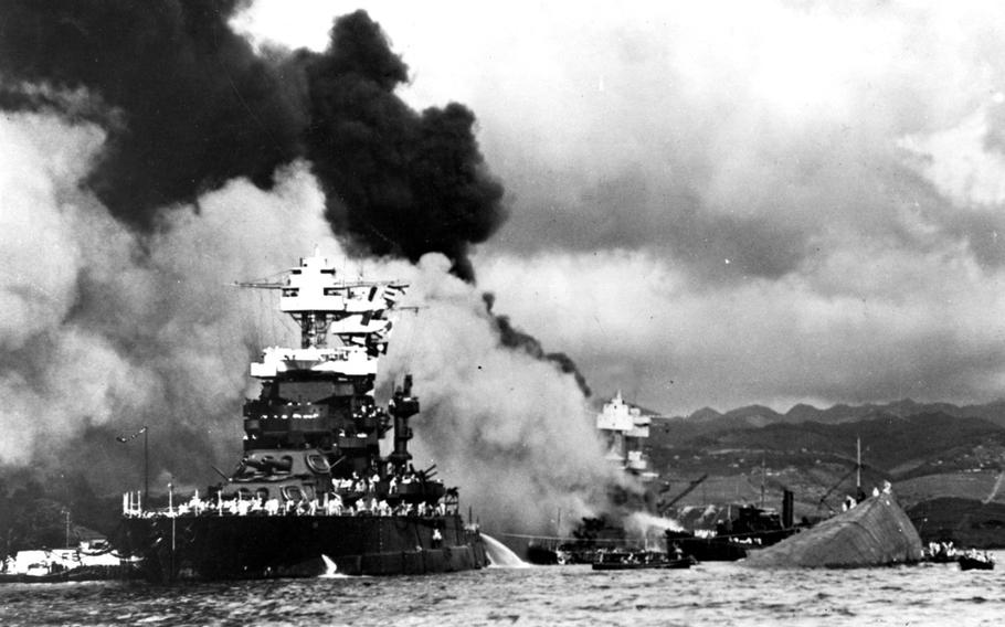 The USS Maryland floats beside the capsized USS Oklahoma, Dec. 7, 1941, as the USS West Virginia burns in the background following Japan's surprise attack on Pearl Harbor, Hawaii.