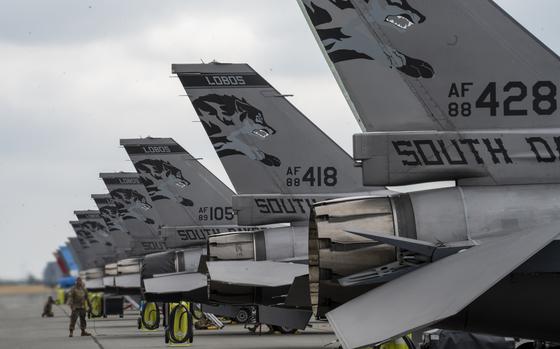 Fighter aircraft are parked in a row on an airfield.