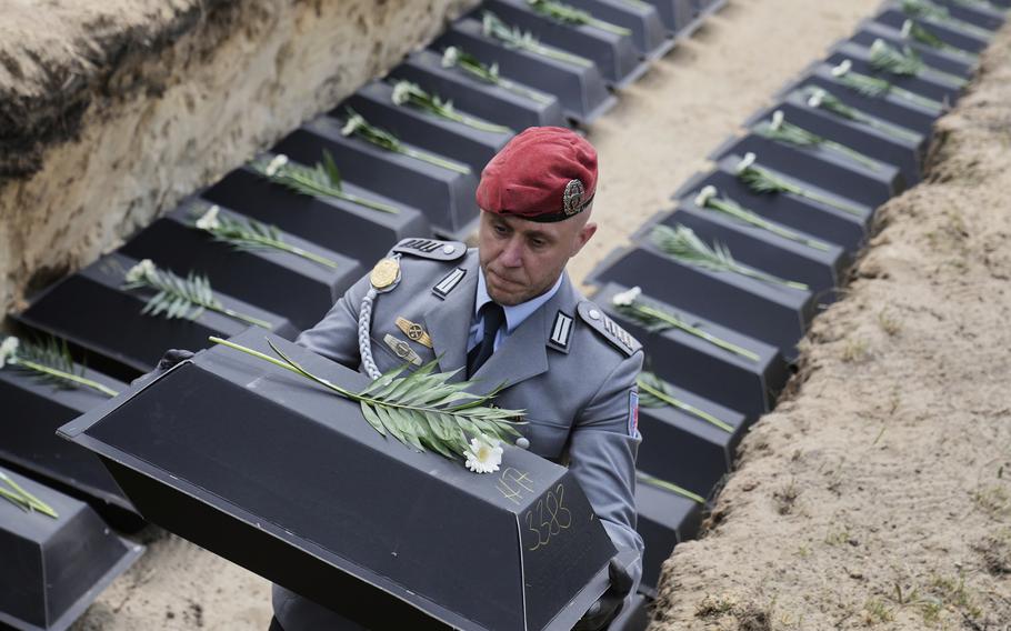 A German soldier holds a black box containing remains. 
