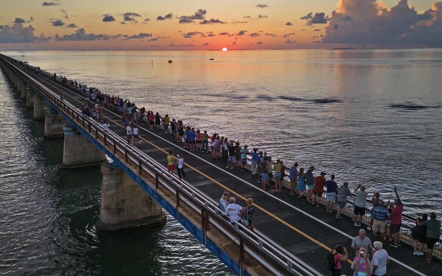 In this aerial photo provided by the Florida Keys News Bureau, attendees watch and toast the sunset at a Florida Keys bicentennial celebration, Friday, May 19, 2023, on the restored Old Seven Mile Bridge in Marathon, Fla.