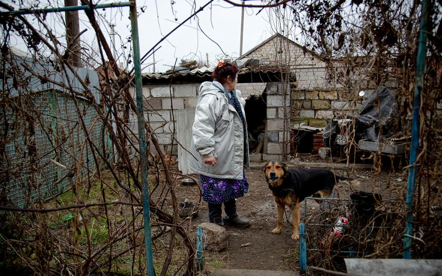 Svetlana Haytulova with her dog in Hranitne, Ukraine, stands in front of her house, which was damaged after shelling in October.