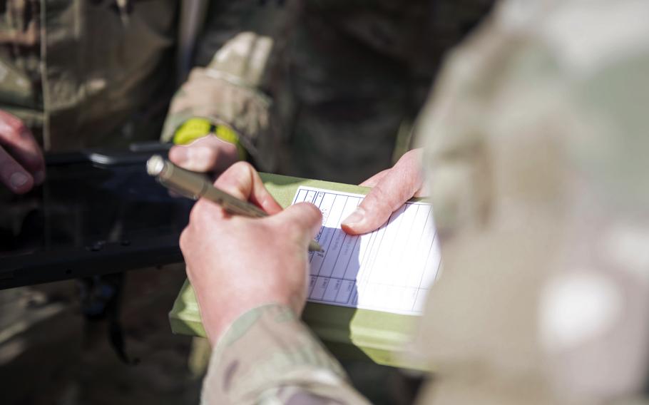 US army soldiers track a simulated adversary on an open field.