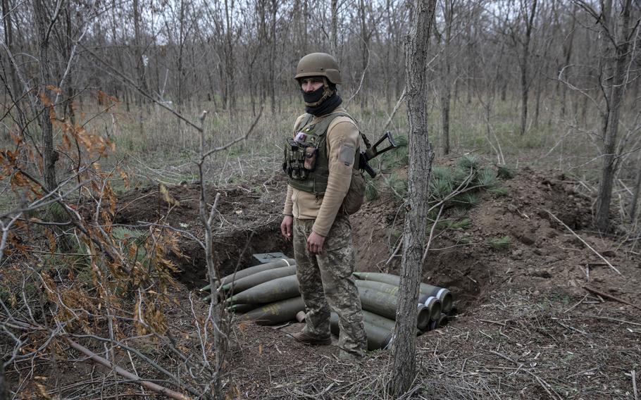 A soldier from the Ukrainian artillery unit stands near a cache of shells.