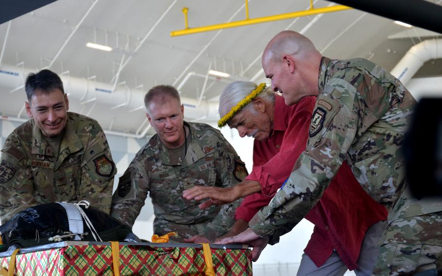 From left to right, Col. Andrew Roddan, Brig. Gen. Paul Birch, Bruce Best and Col. Kyle Benwitz push a supply crate onto a C-130J Super Hercules ahead of Operation Christmas Drop humanitarian airlift missions at Andersen Air Force Base, Guam, Monday, Dec. 5, 2022. 