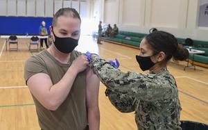 Petty Officer 3rd Class Jasmine Blade, a hospital corpsman, administers a COVID-19 vaccine during a mass-immunization exercise on Naval Air Station Sigonella, Italy, Dec. 7, 2021.  Sigonella has given nearly 1,700 COVID-19 booster shots to adults since Nov. 1.