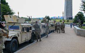 Troops and military vehicles at the Mall, with the Washington Monument in the background.