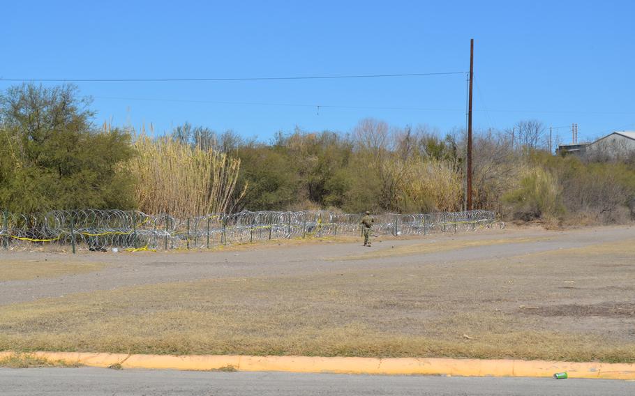 A Texas National Guard soldier walks along a stretch of coiled barbed wire troops placed along the U.S. border with Mexico in Eagle Pass, Texas, on Feb. 14, 2022, as part of a state border security mission.