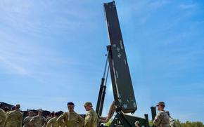 Soliders stand in front of the Dark Eagle hypersonic missile system with a blue sky in the background.