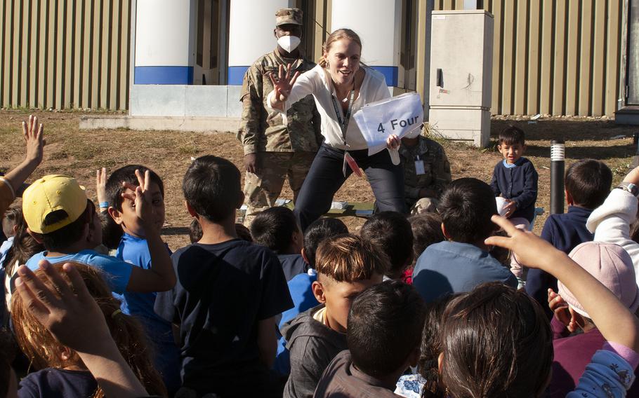 Afghan children hold up four fingers during an English lesson led by volunteer teacher Morgan Guinn at Rhine Ordnance Barracks in Kaiserslautern, Germany, Sept. 23, 2021. The Army facility is housing 5,400 evacuees from Afghanistan until flights to the U.S. resume. 