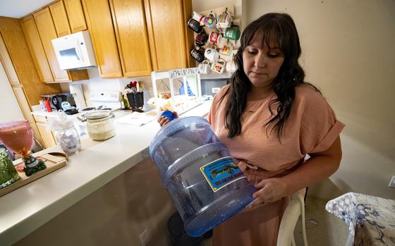 Richelle Dietz holds an empty five-gallon water bottle at her home in Joint Base Pearl Harbor-Hickam, Monday, April 22, 2024, in Honolulu, Hawaii. The Dietz family relies on bi-weekly water deliveries for basic needs since their water was tainted in 2021.