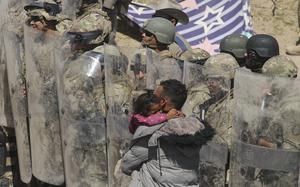 A Venezuelan migrant man carries one of his daughters while being forced to retreat by anti-riot members of the Texas National Guard and highway police who stand guard on the banks of the Rio Grande river to prevent the arrival of migrant people to the U.S,. as seen from Ciudad Juarez, Chihuahua state, Mexico on March 22, 2024. (Herika Martinez/AFP/Getty Images/TNS)