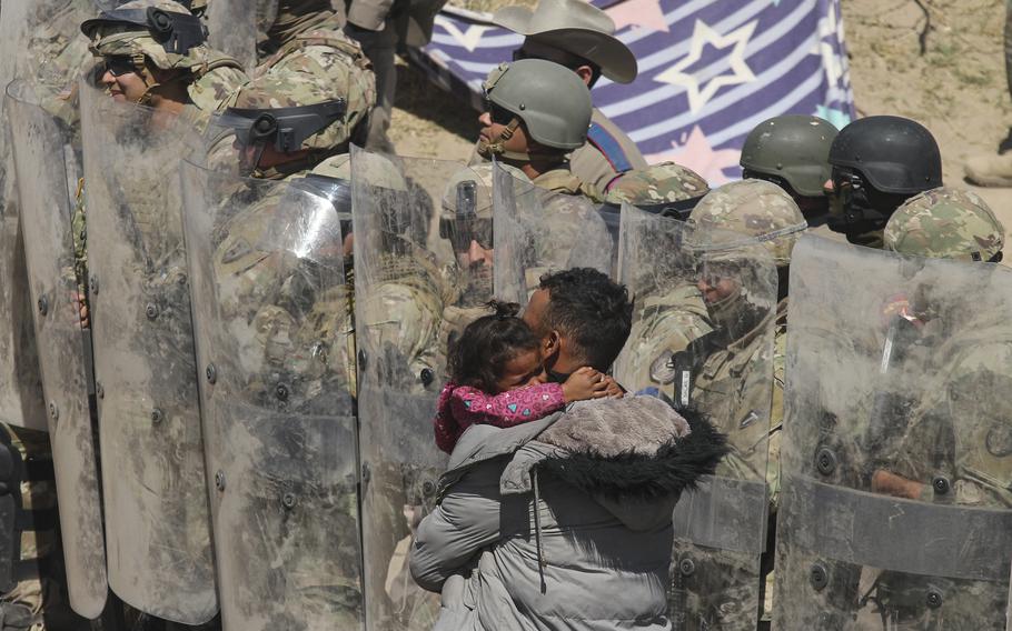 A Venezuelan migrant man carries one of his daughters while being forced to retreat by anti-riot members of the Texas National Guard and highway police who stand guard on the banks of the Rio Grande to prevent the arrival of migrant people to the U.S., as seen from Ciudad Juarez, Chihuahua state, Mexico, on March 22, 2024.