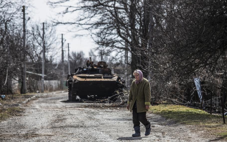 A woman walks by a destroyed Russian military vehicle on the outskirts of Brovary, Ukraine, on March 28, 2022. 