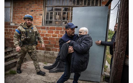 A man helps his elderly father, who is unable to walk, out of his house as Kharkivskyi evacuates civilians from Vovchansk on Monday. MUST CREDIT: Ed Ram for The Washington Post