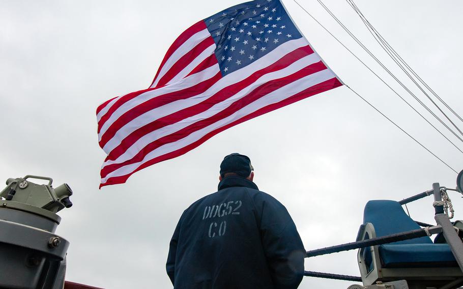 Cmdr. Chris Gahl watches as the flag is raised aboard the USS Barry while the guided-missile destroyer sails through the Taiwan Strait, Nov. 21, 2020. 