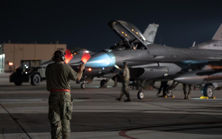 An airman marshals an aircraft.