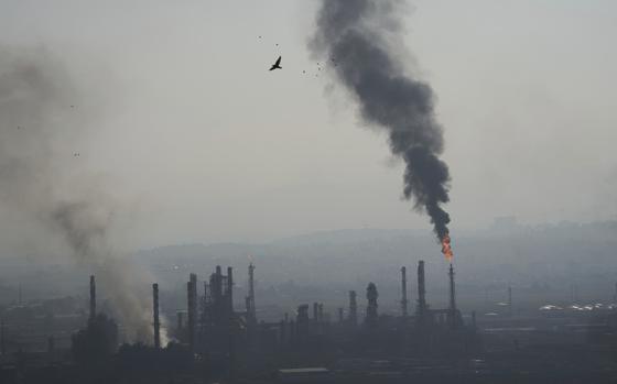 Smoke billows from an oil refinery.